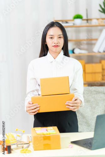  woman sit at workplace desk laughing working on-line using laptop in warehouse. 