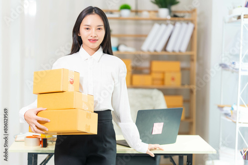  woman sit at workplace desk laughing working on-line using laptop in warehouse. 