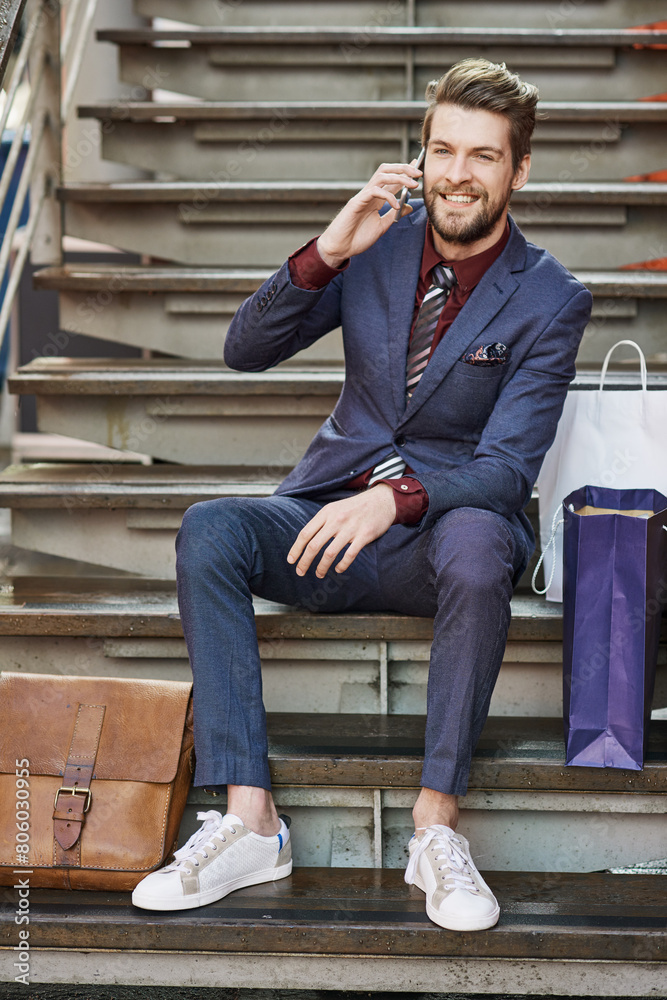Man, smartphone and call on stairs for fashion, communication and style in mall. Personal stylist, phone and confidence for shopping, clothes and trendy suit with conversation, bags and happiness Man, smartphone and call on stairs for fashion, communication and style in mall. Personal stylist, phone and confidence for shopping, clothes and trendy suit with conversation, bags and happiness