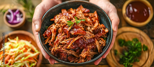 hands of cook serving a barbecue pulled pork, made from slow-cooked pork shoulder or pork butt, shredded, and then mixed with a tangy and sweet barbecue sauce photo