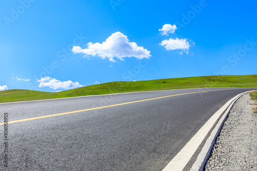 Asphalt highway road and green meadow with mountain nature landscape under blue sky