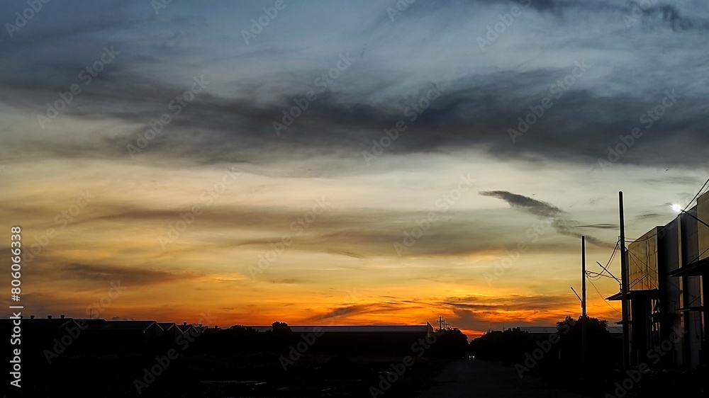 Obraz premium Silhouette of warehouse and industrial area during beautiful dramatic sunset