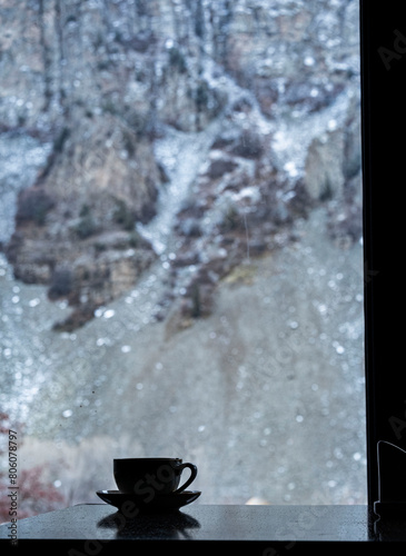 Hot coffee cup in front of Snowy Mountain Rock Landscape