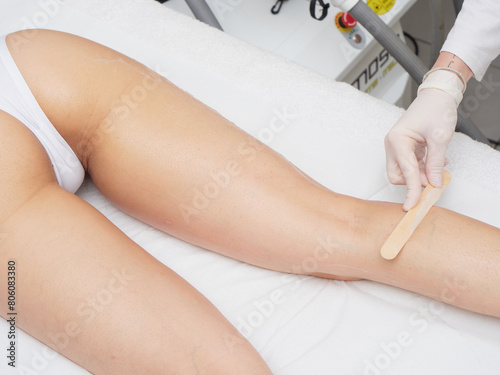 Beautician applying wax before Removing Hair Of Young Woman’s body