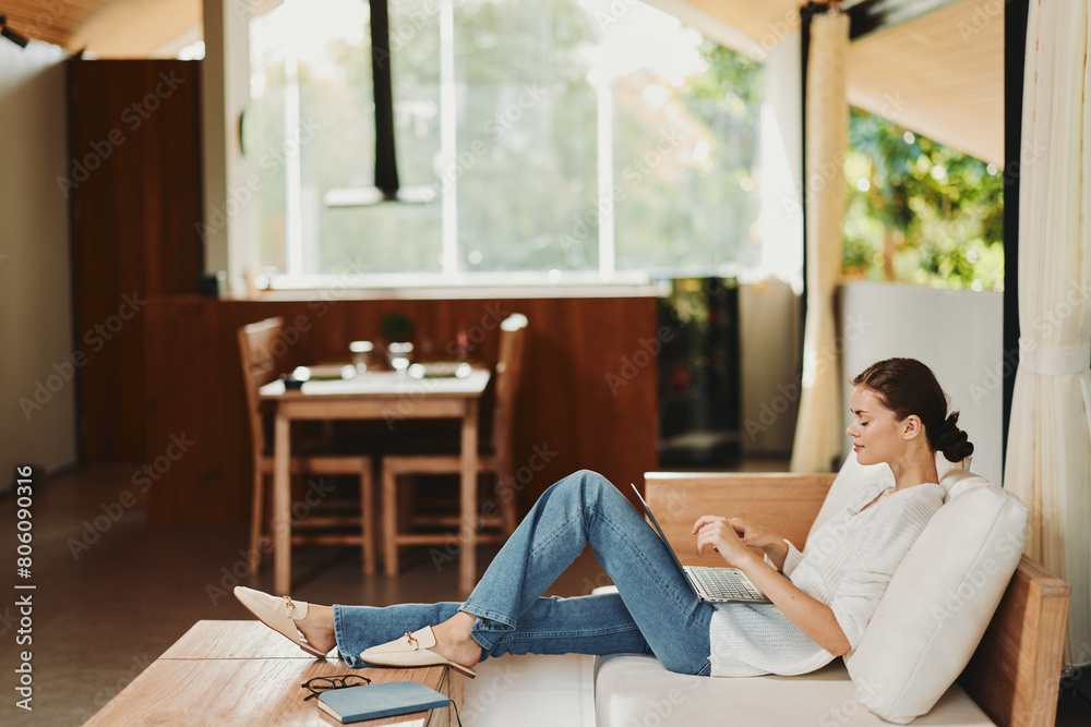 Relaxed Woman Enjoying a Cozy Weekend at Home, Chatting Online and Shopping on Her Laptop in a Modern Living Room Relaxed Woman Enjoying a Cozy Weekend at Home, Chatting Online and Shopping on Her Laptop in a Modern Living Room