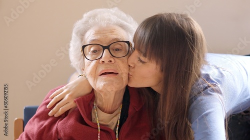 Granddaughter embracing and kissing her grandmother in a geriatric