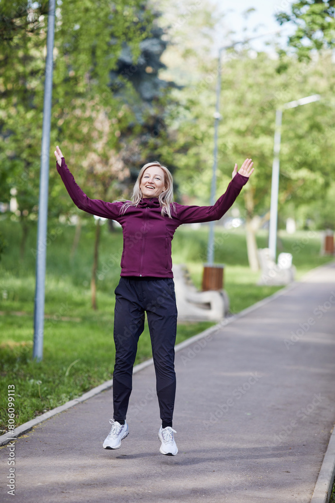 Middle-aged woman with arms outstretched in joy while walking in a park