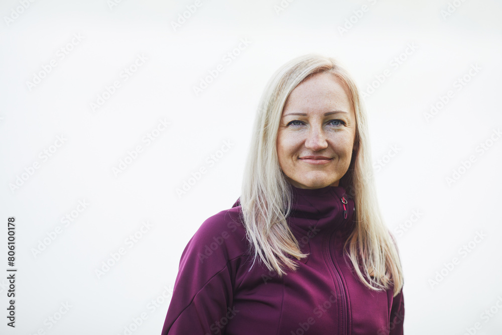 Close-up of a middle-aged woman in sportswear, serene against a foggy backdrop Close-up of a middle-aged woman in sportswear, serene against a foggy backdrop