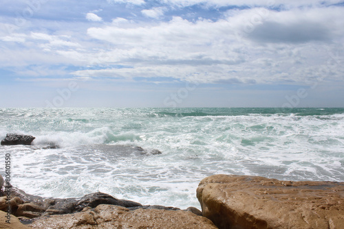 Fototapeta Naklejka Na Ścianę i Meble -  travel, sea wave on rocks against cloudy sky, sea coast with waves, waves on the beach, natural background texture of sea sky and stones