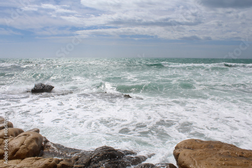 Fototapeta Naklejka Na Ścianę i Meble -  travel, sea wave on rocks against cloudy sky, sea coast with waves, waves on the beach, natural background texture of sea sky and stones