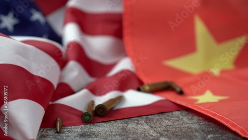 Hand of unrecognizable person pushing two bullets in the middle of an American and Chinese flag. 