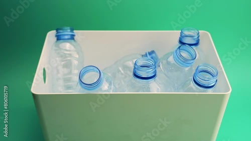 From above recycled open empty plastic bottles in white box placed on green surface.