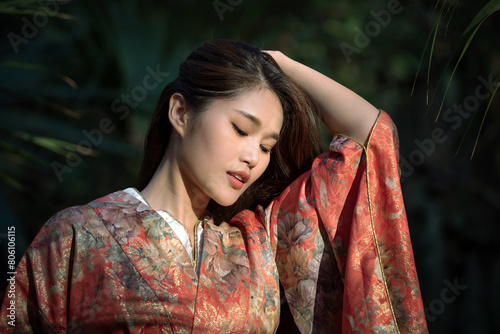 Portrait of beautiful young Asian woman wearing a kimono against a blurred forest background. Japanese traditional clothes.