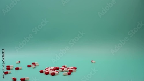 High angle of crop unrecognizable male patient showing handful of white and red pills at green table