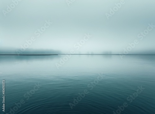 Misty lake with distant shoreline and trees in the fog