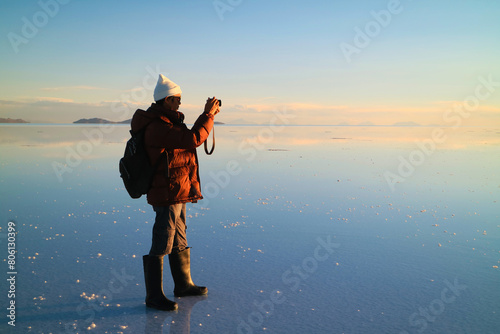 Traveler Shooting Photos on the Amazing Mirror Effect of Uyuni Salt Flats at Sunset, Bolivia, South America