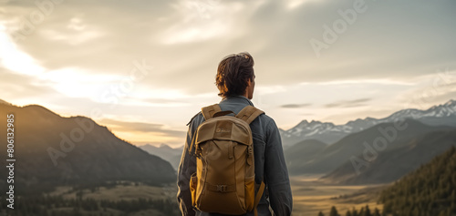 Back view of a man with a backpack standing against a breathtaking mountain landscape at sunset  contemplating nature. 