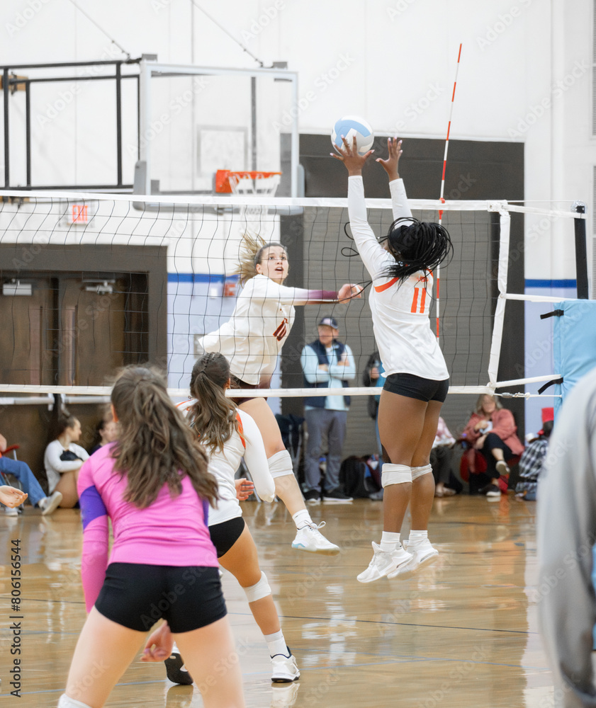 College volleyball players at the net hitting and blocking