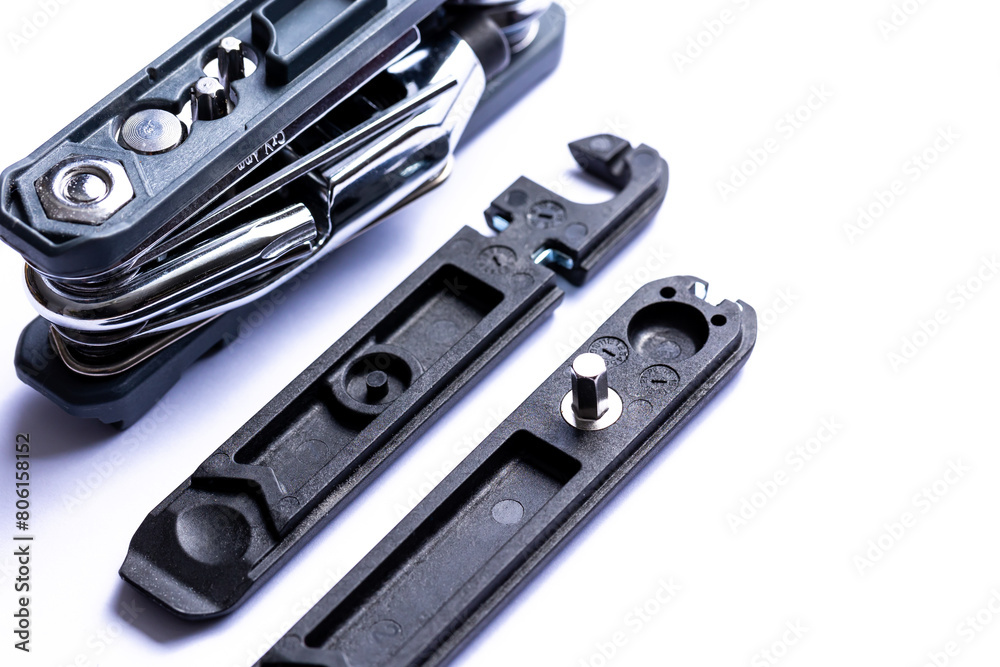 Fototapeta premium Black bicycle multifunctional multitool unfolded on a white background. Chrome steel tools. Tools for bicycle self-repairing .