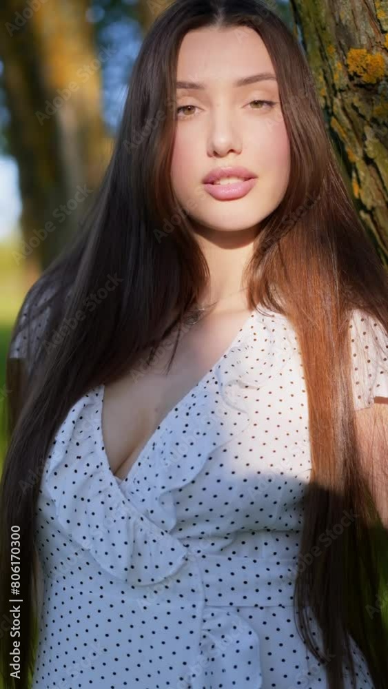 A long-haired brunette in nature on a summer day.Beautiful girl in a white dress outdoors in summer
