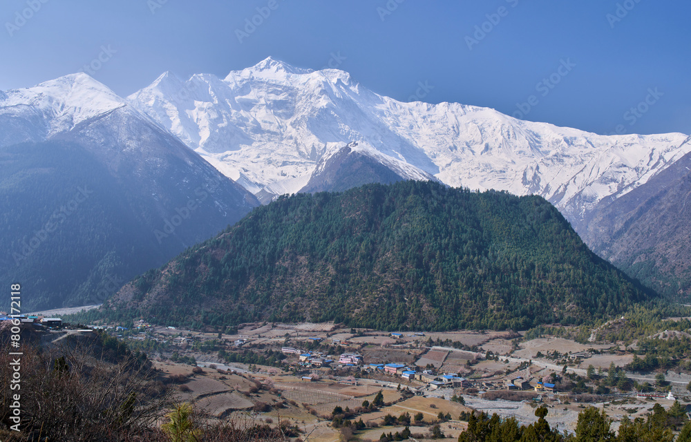 Panoramic view on the village Lower Pisang and the summit of the Annapurna II as seen from the village Upper Pisang. Annapurna Circuit trek, the most popular trek in Nepal.