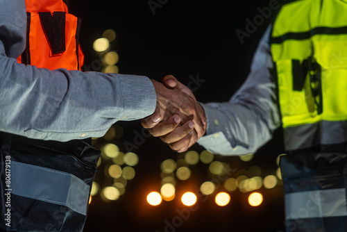 Night scene. Close up of Asian man petrochemical engineers shaking hands together after going through routine checks at petroleum oil refinery in industrial estate. photo