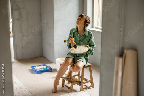 Fotografie Woman paints walls renovating her apartment