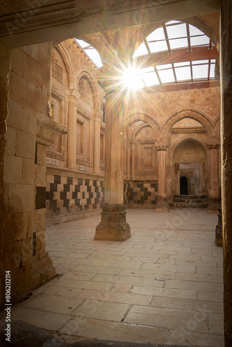 Vertical shot of sun shining through historical Arabian palace interior with arcs and columns