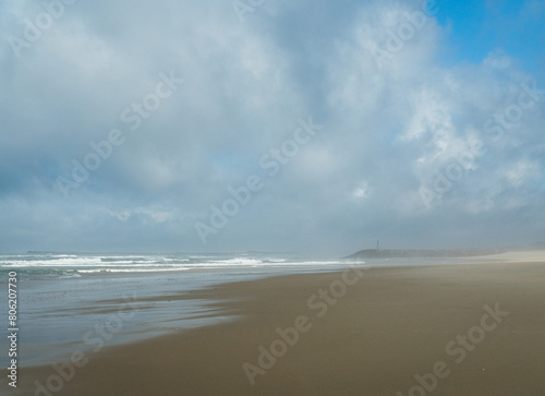 The waves of the Atlantic Ocean wash the sandy beach  the horizon is visible  the day is overcast.