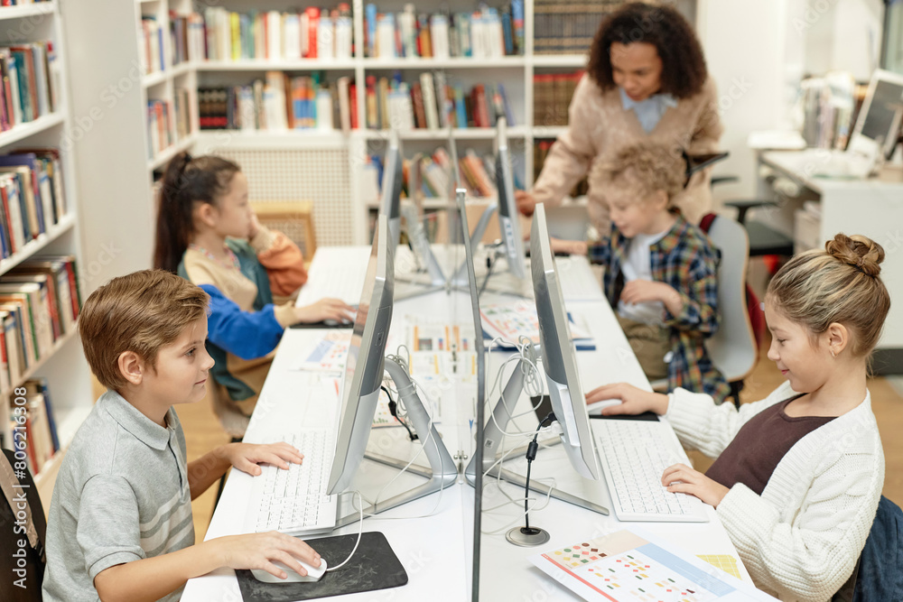 Fototapeta premium High angle view at group of young school children using computers during IT programming class for kids and smiling