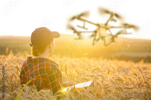 Woman farmer controls drone sprayer with a tablet. Smart farming and precision agriculture.. © scharfsinn86