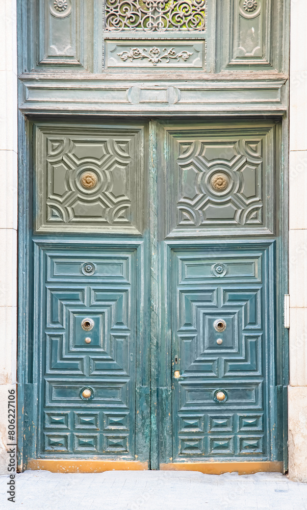 A wooden door with a handle in the wall of the house in close-up - Madrid, Spain A wooden door with a handle in the wall of the house in close-up - Madrid, Spain