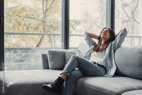 Relaxed serene pretty young woman feel fatigue lounge on comfortable sofa hands behind head rest at home, happy calm lady dream enjoy wellbeing breathing fresh air in cozy home modern living room.