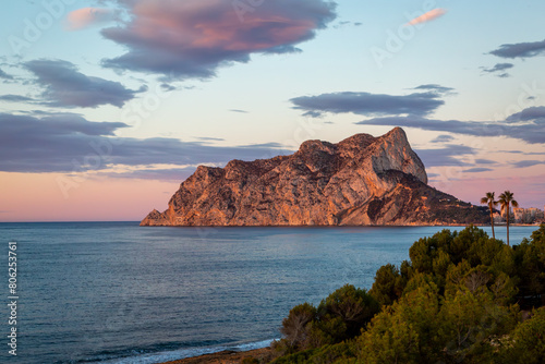 Sunrise view of Penyal d'Ifac Natural Park from along the coast, Image shows the beautiful sunrise lighting up the sky with various colours and the massive rock in the national park located in Calp
