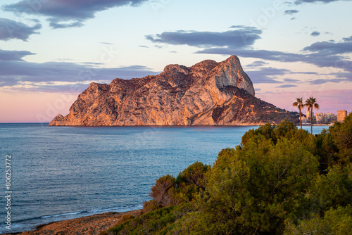 Sunrise view of Penyal d'Ifac Natural Park from along the coast, Image shows the beautiful sunrise lighting up the sky with various colours and the massive rock in the national park located in Calp