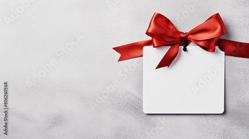 Blank white empty price tag, white note or gift card mock up with red gift ribbon bow on grey wall background with shadow, Merry Christmas and New Year decoration, generative AI