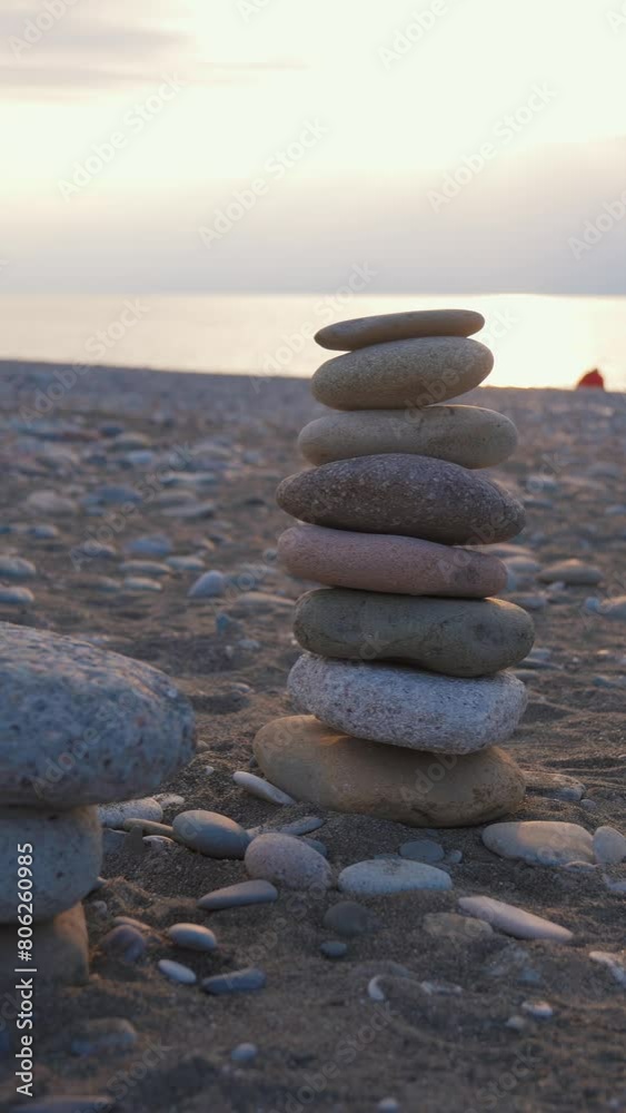 Spiritually relaxed woman putting stone on pyramid of cobblestones on pebble beach by sea at sunset. Yoga female peace of mind relax meditation harmony life balance tranquility equilibrium pyramid Spiritually relaxed woman putting stone on pyramid of cobblestones on pebble beach by sea at sunset. Yoga female peace of mind relax meditation harmony life balance tranquility equilibrium pyramid