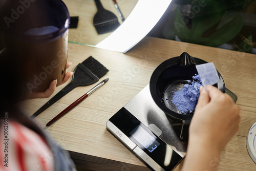 Tableau sur toile High angle closeup of hairstylist mixing bleach in plastic bowl and weighing sol