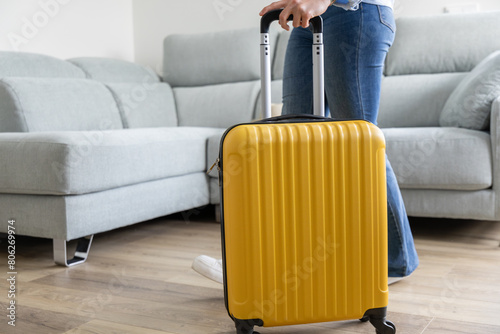 girl leaving home with her yellow wheeled suitcase to go on a family trip photo