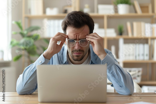 Man Sitting at Table Looking at Laptop