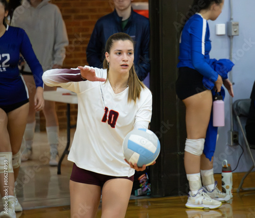 Female college volleyball player getting ready to serve