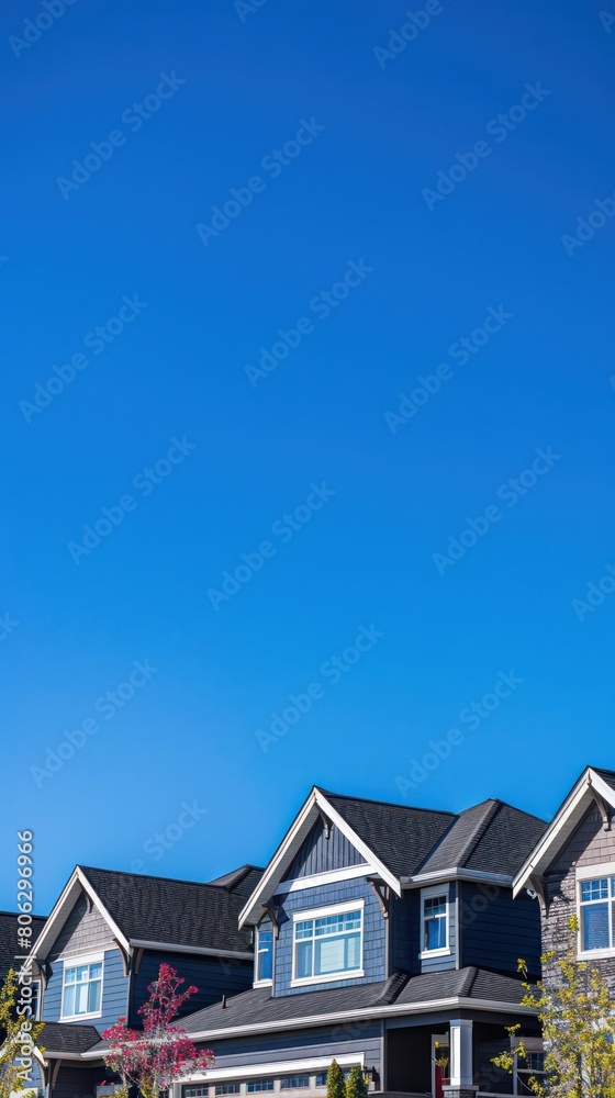 A vivid blue sky stretches above a row of modern dark blue townhouses with striking architectural features A vivid blue sky stretches above a row of modern dark blue townhouses with striking architectural features