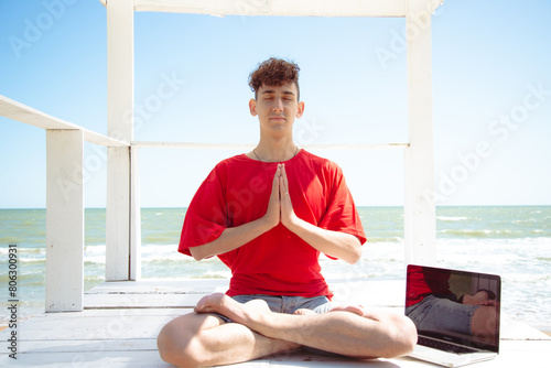A young attractive student is relaxing by the seashore and doing yoga.