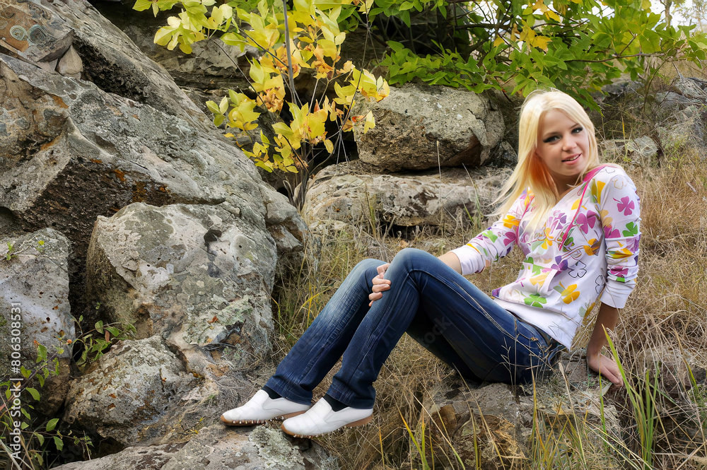 A young beautiful girl posing against the background of large stones.