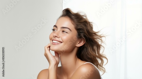 Young beautiful woman with perfect skin smiling and touching her face photo