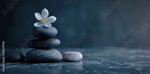 zen stones and a white flower on a grey background.