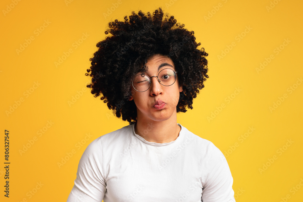 Humorous emotional portrait of grimacing young black man, blowing cheeks on orange background Humorous emotional portrait of grimacing young black man, blowing cheeks on orange background