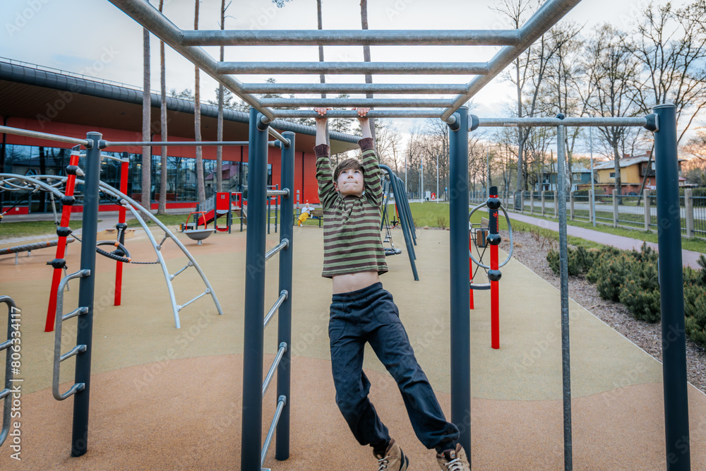 Fototapeta premium boy was hanging upside down on the bars. Smiling happy child