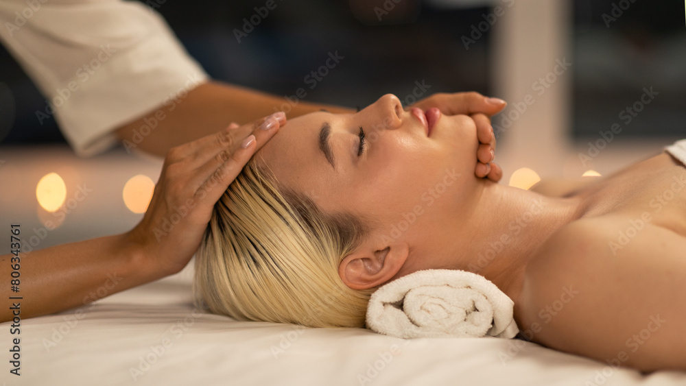 Obraz premium The photo shows a blonde woman lying down during a facial massage at a spa, with a calm and peaceful expression, enhancing her youthful glow