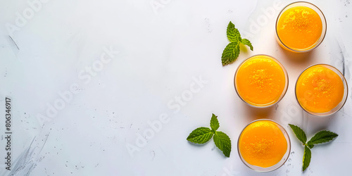 Four small cups of orange juice with mint leaves. photo